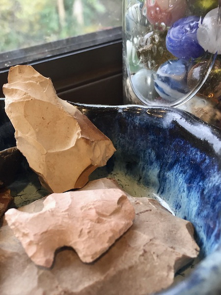 arrowheads in blue pottery bowl by jar of marbles